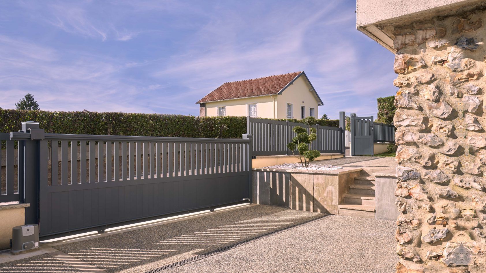 Image d'un portail coulissant 3m en aluminium gris anthracite installé devant une maison moderne.